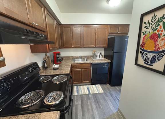 A kitchen with a black stove top oven and a black refrigerator.