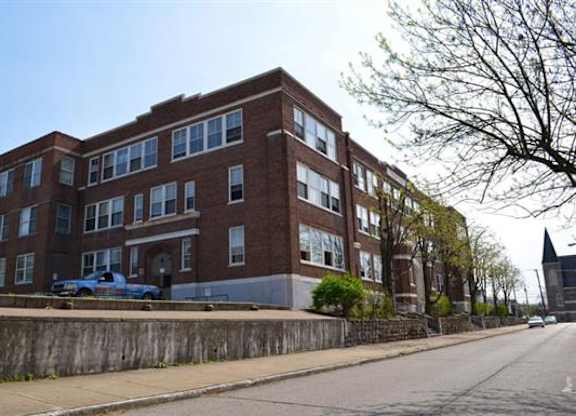 A large red brick building with a blue truck parked in front.