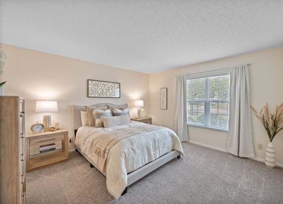 A bedroom with a large bed and a window with curtains.