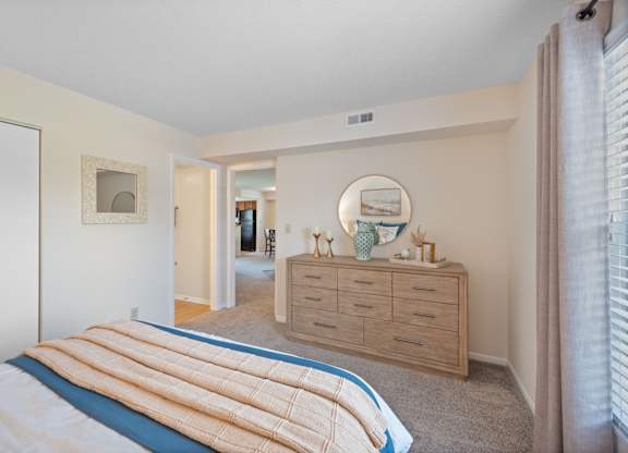 A bedroom with a bed, dresser, and mirror.