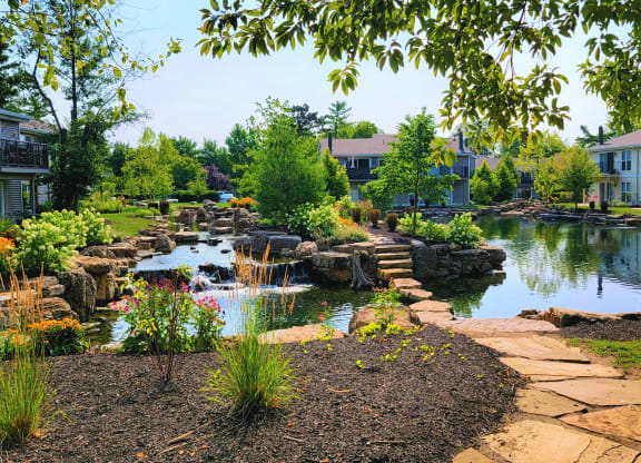 a garden with a pond and bridge in front of a building at Harpers Point Apartments, Ohio, 45249