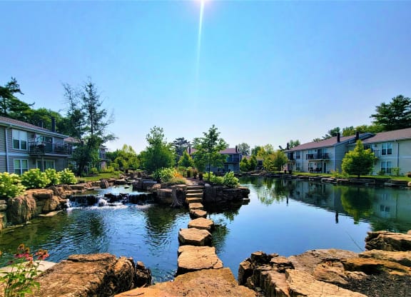 a pond with rocks and waterfall in front of an apartment complex at Harpers Point Apartments, Cincinnati, Ohio