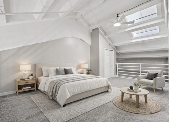 A bedroom with a large bed and a chair.