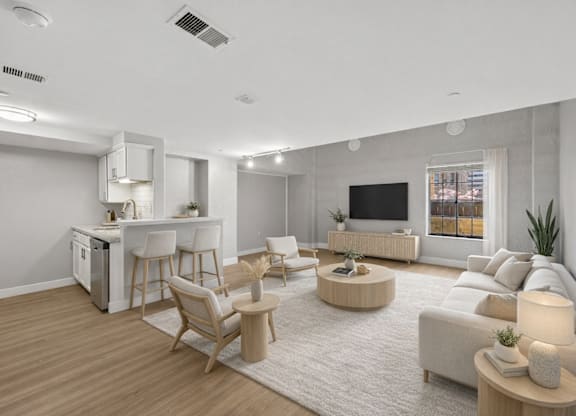 A modern living room with a kitchen area in the background.