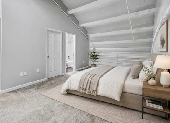 A bedroom with a bed, nightstand, and a plant.