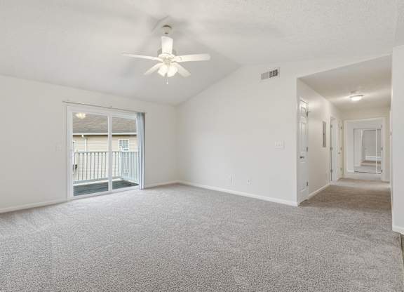 A spacious room with a ceiling fan and carpeted floor.