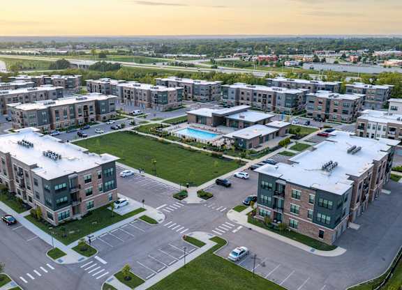 A large apartment complex with a parking lot in front.