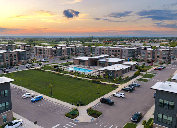 A sunset view of a parking lot with cars and apartment buildings.