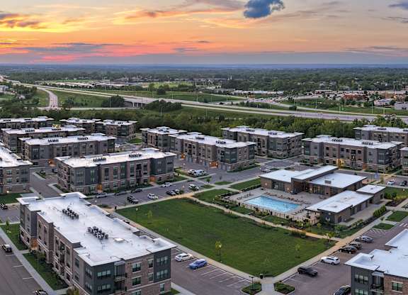 A sunset view of a residential area with apartment buildings, with garages and a pool.