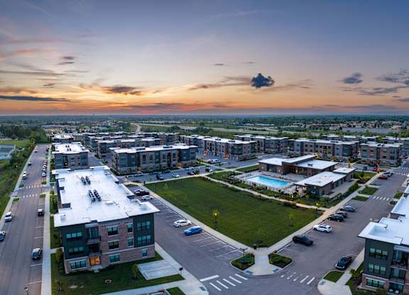 A sunset view of a residential area with apartment buildings and a pool.