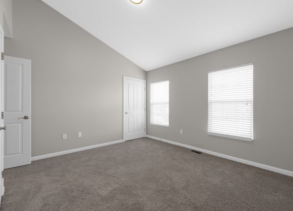 an empty living room with a door and two windows at Traditions at Slate Ridge, Reynoldsburg Ohio