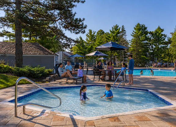 A group of people are enjoying a sunny day at a poolside.