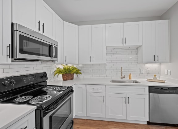 a white kitchen with black appliances and white cabinets at Monmouth Row Apartments, Kentucky