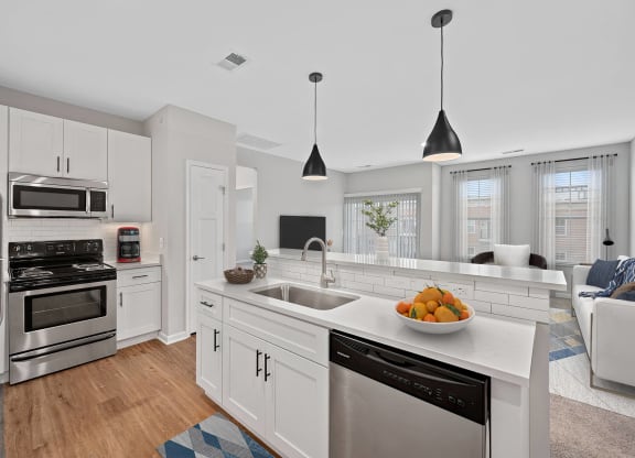 a white kitchen with a large counter top and a sink at Monmouth Row Apartments, Newport, KY, 41071