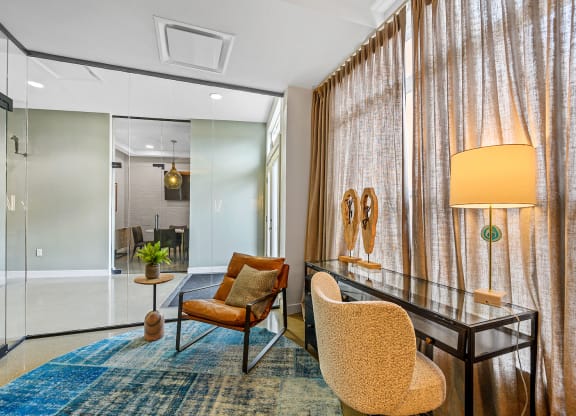 a living room with a desk and chairs and a large curtain