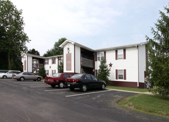 a parking lot with cars in front of a white and brown apartment complex at Ridgeview, Fortville, IN