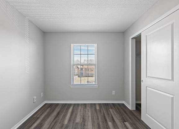 A room with a window showing a building outside.