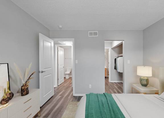 A bedroom with a bed, nightstand, and a green rug.