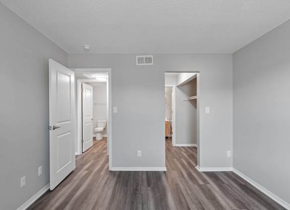 A long, narrow hallway with wood floors and white walls.