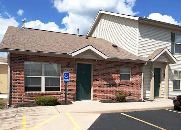 A small brick building with a green door and a handicap sign on the window.