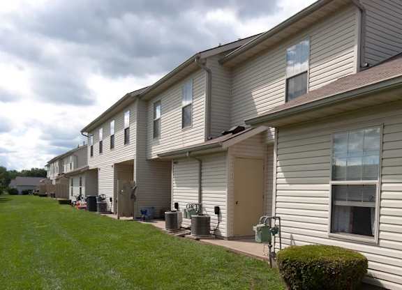 A row of houses with green lawns and a cloudy sky.