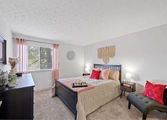 A bedroom with a bed, nightstand, and chair.