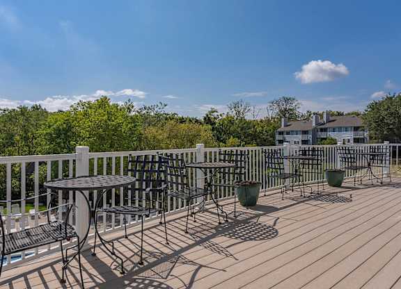 A wooden deck with a table and chairs overlooking a pool.