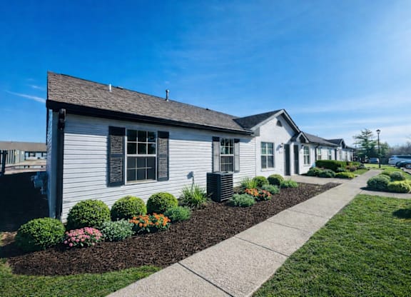 A white house with a brown roof and a grey front yard.