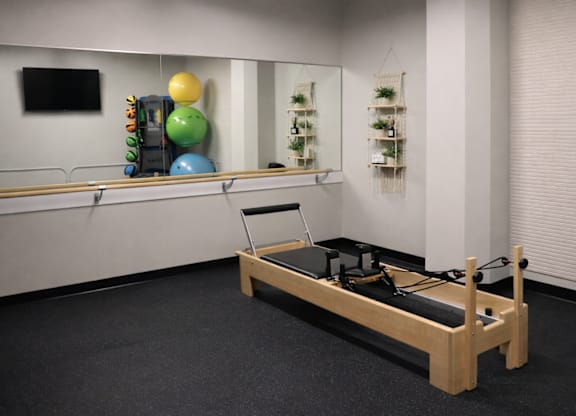 A pilates reformer is in a room with a mirror and balloons.