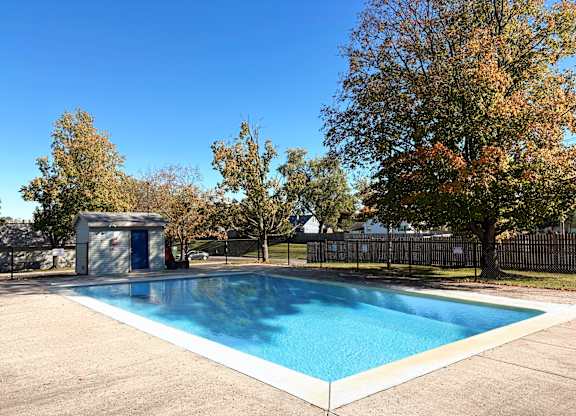 A small pool surrounded by a fence and trees.