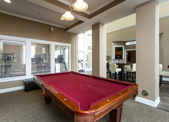 a red pool table in a clubhouse with a dining room in the background