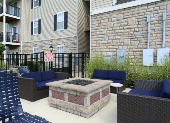 an outdoor patio with a fire pit and chairs in front of an apartment building