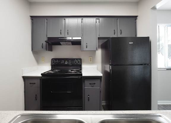 A black stove and oven in a kitchen with a black fridge.