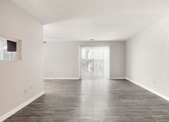 A large empty room with a wooden floor and white walls.