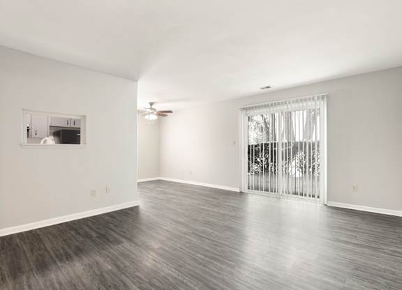 A spacious room with a sliding glass door leading to a balcony.