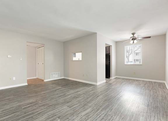 A spacious room with a ceiling fan and light wood flooring.