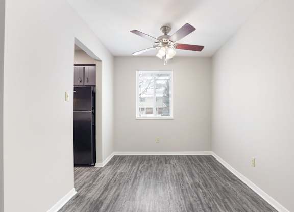 A room with a ceiling fan and a fridge in it.