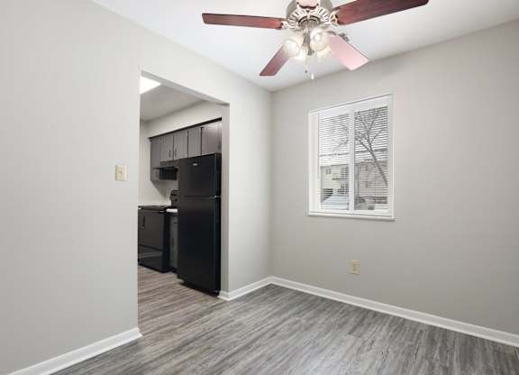 A room with a ceiling fan and a window with blinds.