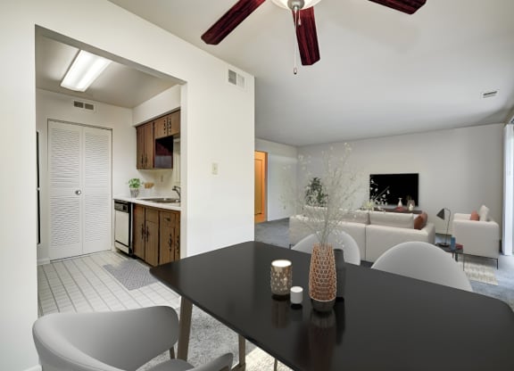 a dining room with a black table and chairs and a living room with white furniture at Quail Run Apartments, Indiana