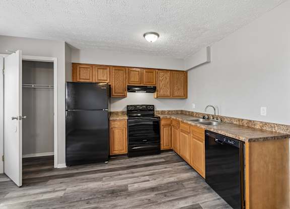A kitchen with black appliances and wooden cabinets. at Sharon Green Townhomes, Columbus