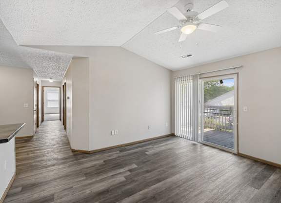 A spacious room with a ceiling fan and sliding glass doors leading to a patio.