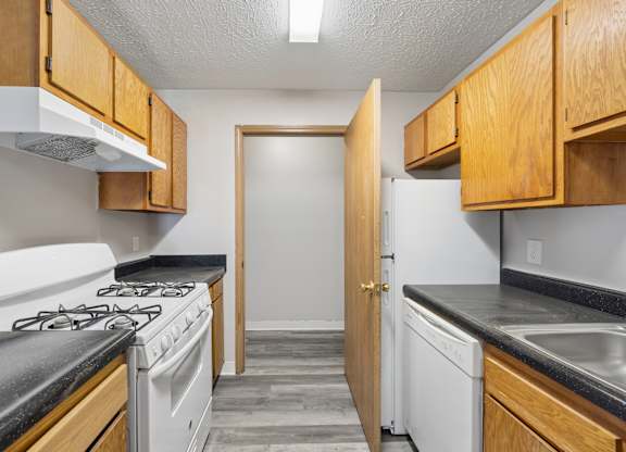 A kitchen with a white stove and wooden cabinets.