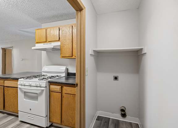 A white stove is in a kitchen with wooden cabinets.