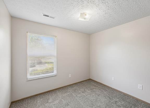 A room with a window and carpeted floor.
