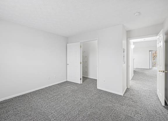 A room with white walls and a grey carpet.