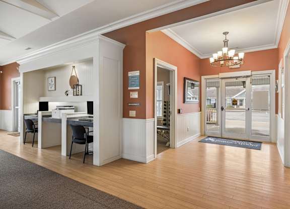 A hallway with a desk and chairs on the left and a doorway to another room on the right.