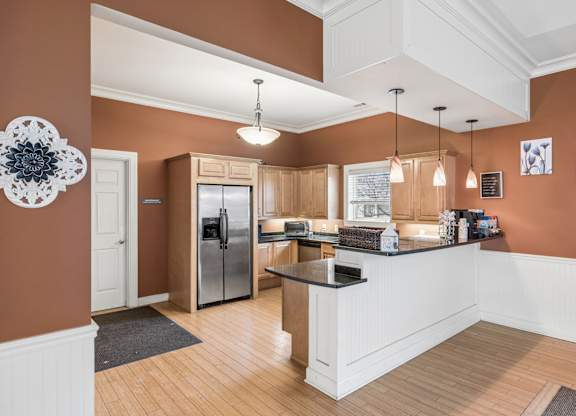 A kitchen with a refrigerator, sink, and cabinets.