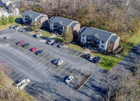 A parking lot with cars and a bus in front of apartment buildings.