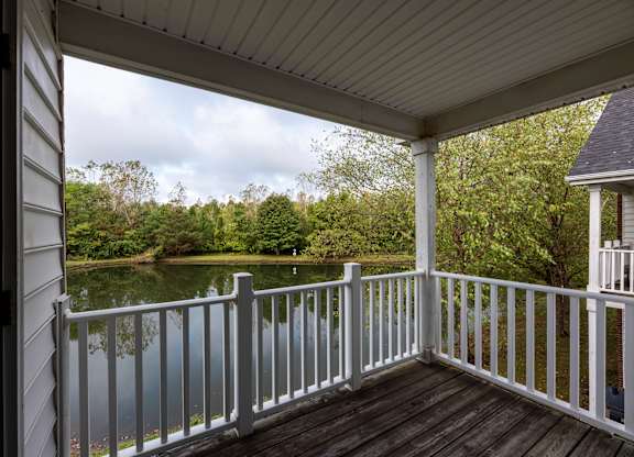 A porch with a view of a lake and trees.