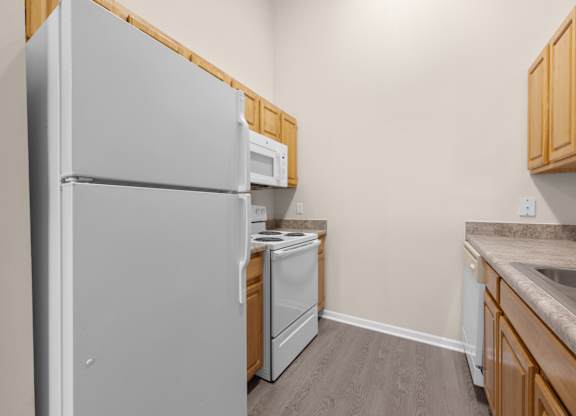 A kitchen with a refrigerator, microwave, dishwasher, and sink.